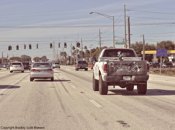 Pickup truck and other vehicles driving on wide suburban road