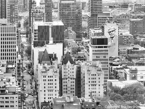 Black and white image of Montreal skyline with mural of Leonard Cohen