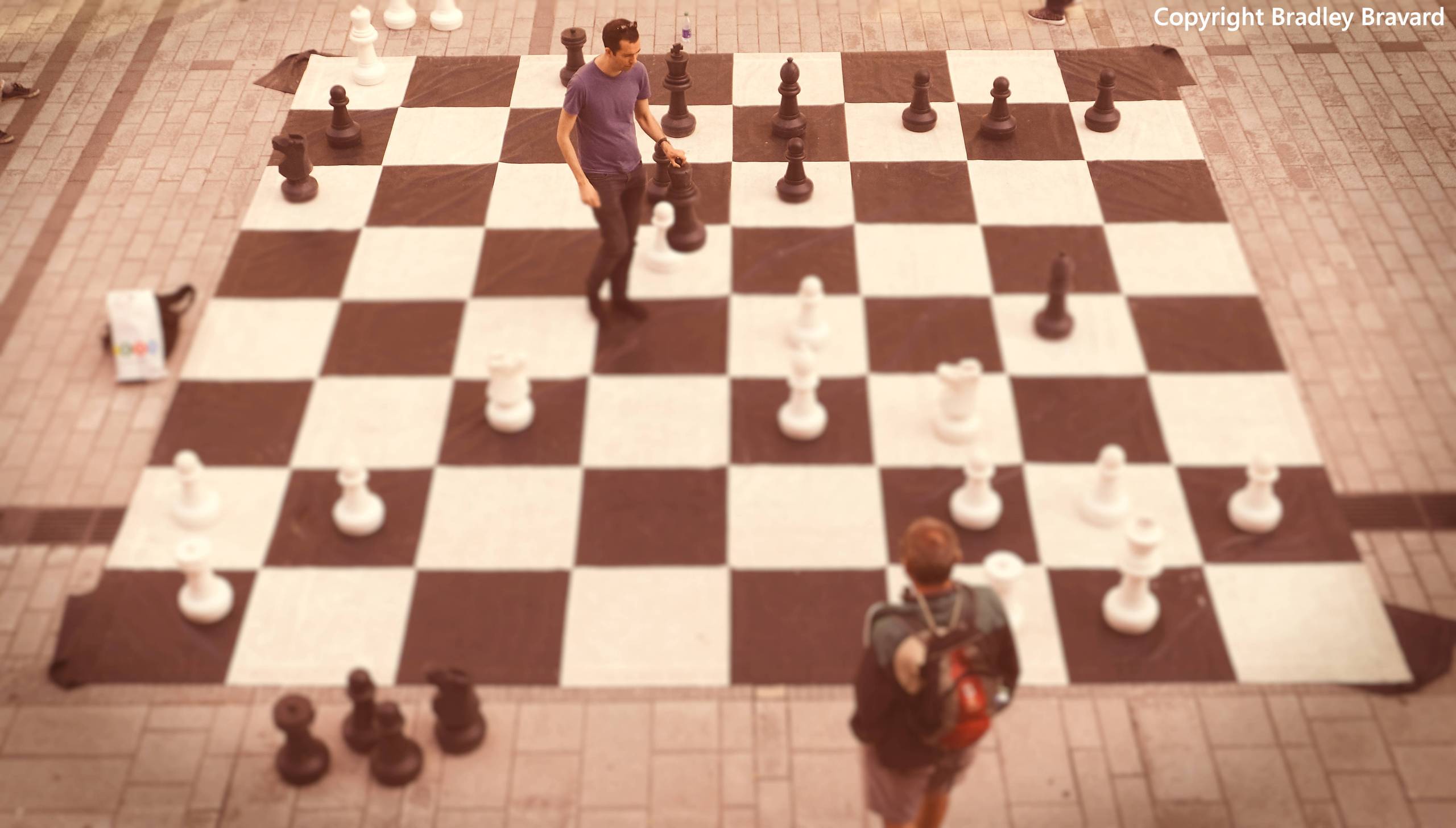Photograph of 2 men playing chess on a very large chess board