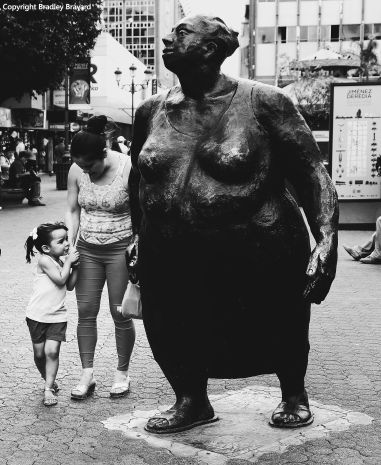 Mother and daughter standing next to sculpture of woman in San Jose, Costa Rica