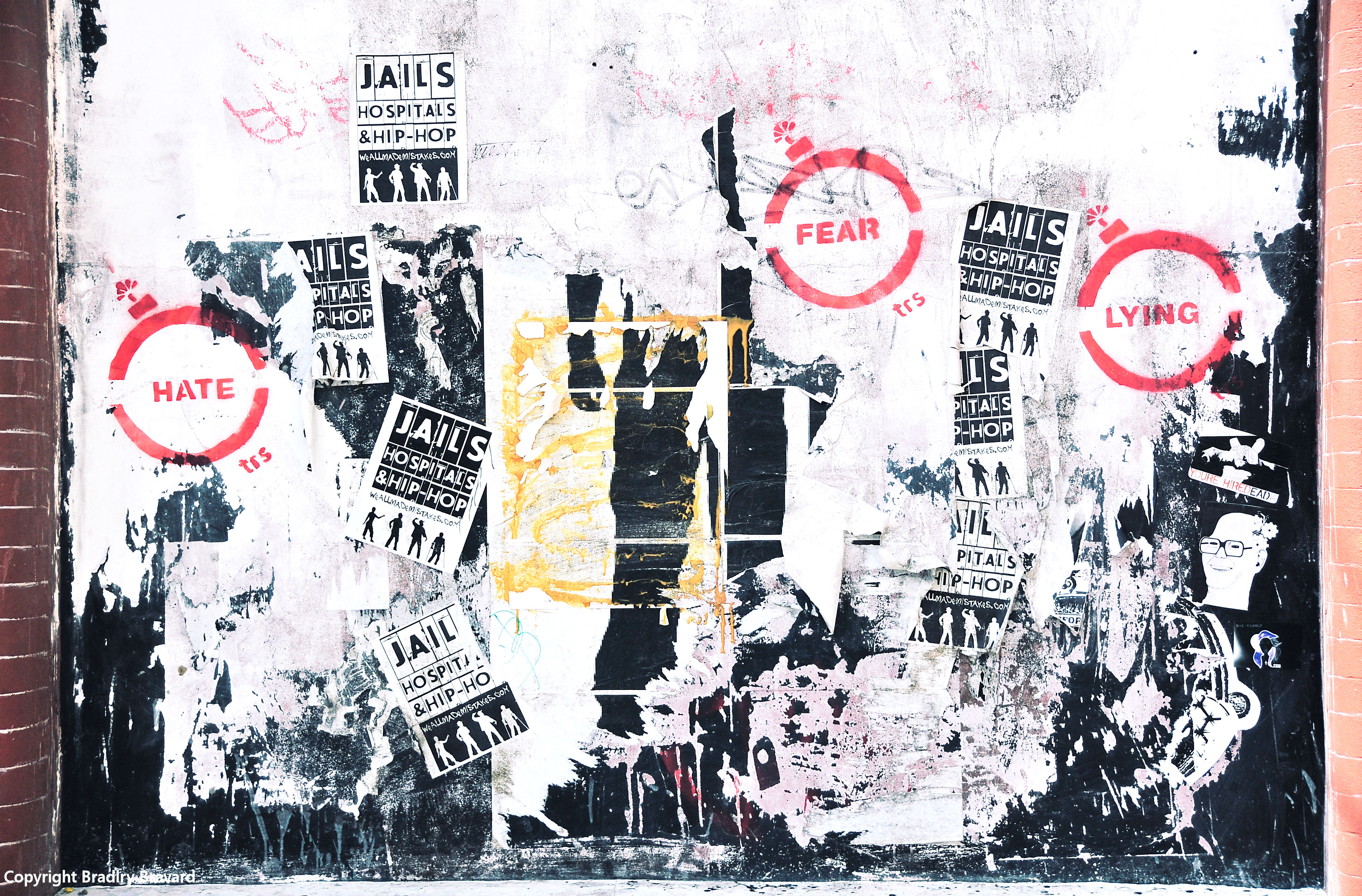 Photo of wall with multiple posters and graffiti overlapping each other