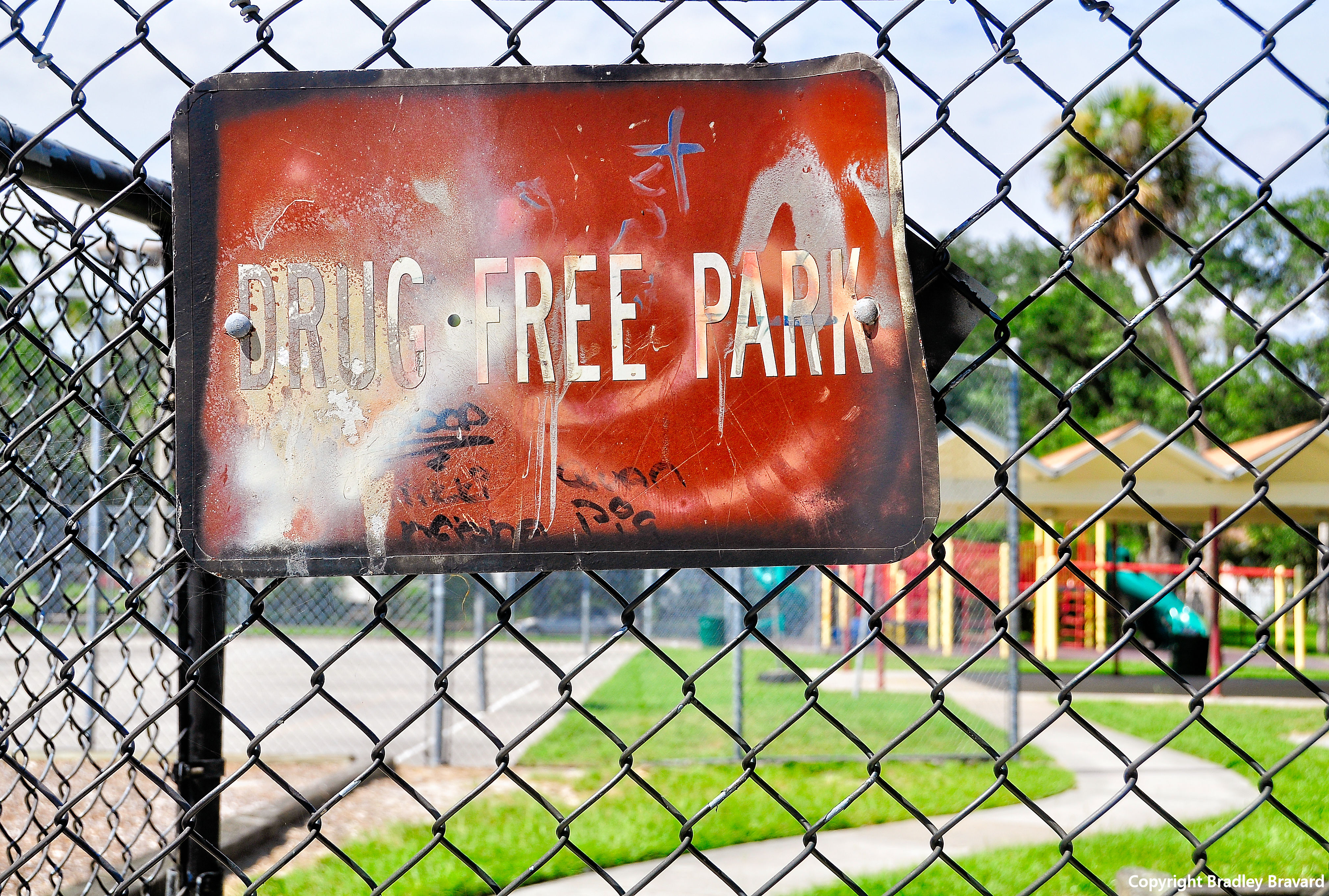 Photo of "Drug Free Park" sign on chain link fence surrounding a park