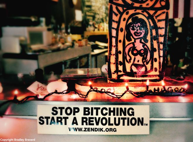 Interior of coffee shop with sticker reading "Stop bitching, start a revolution" and hand-painted pinup art