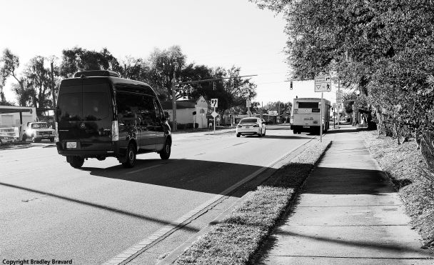Black and white photo of street with van, car, and bus