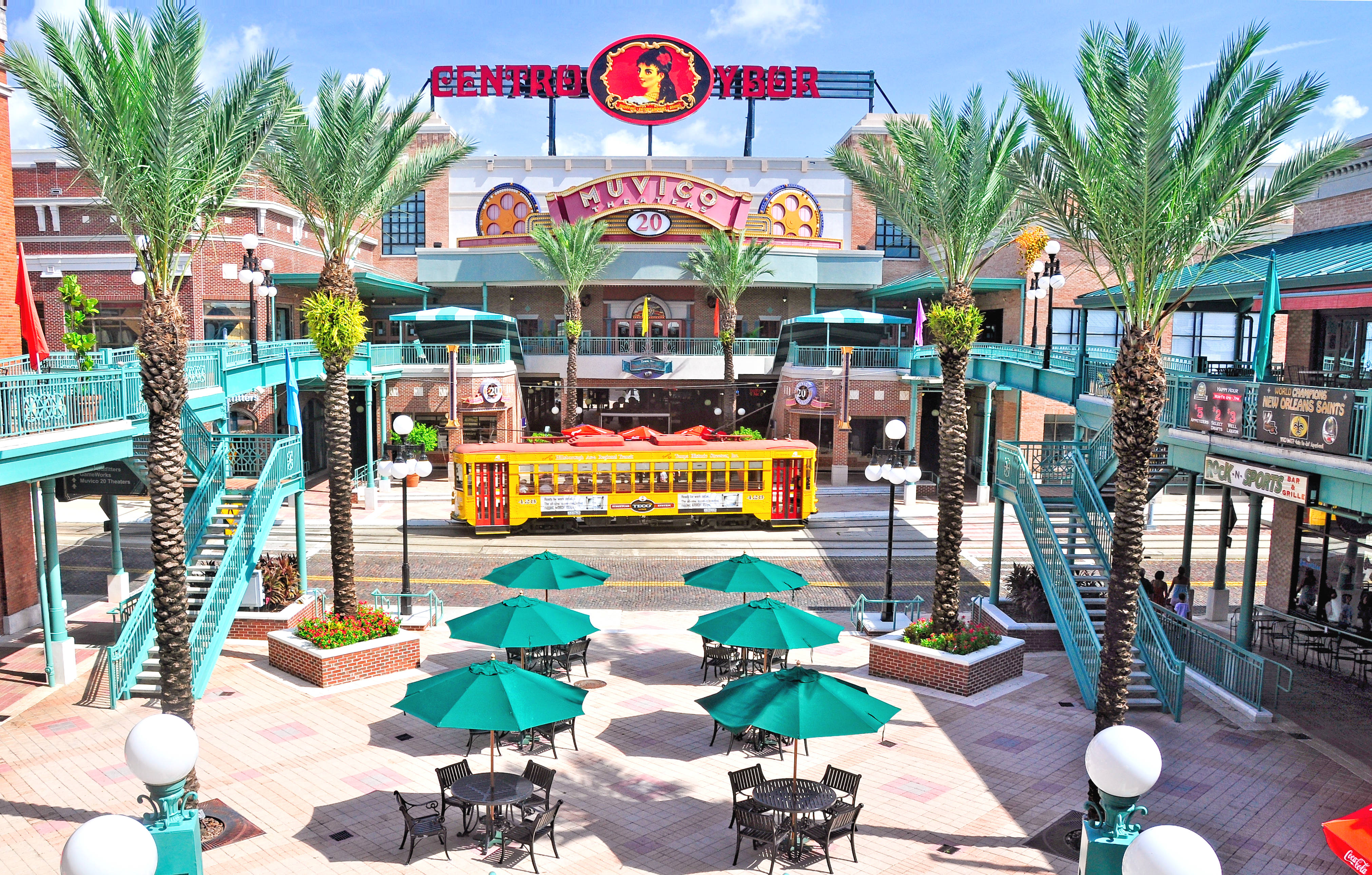 Photo of Centro Ybor shopping center with palm trees, pedestrian mall, and yellow trolley car
