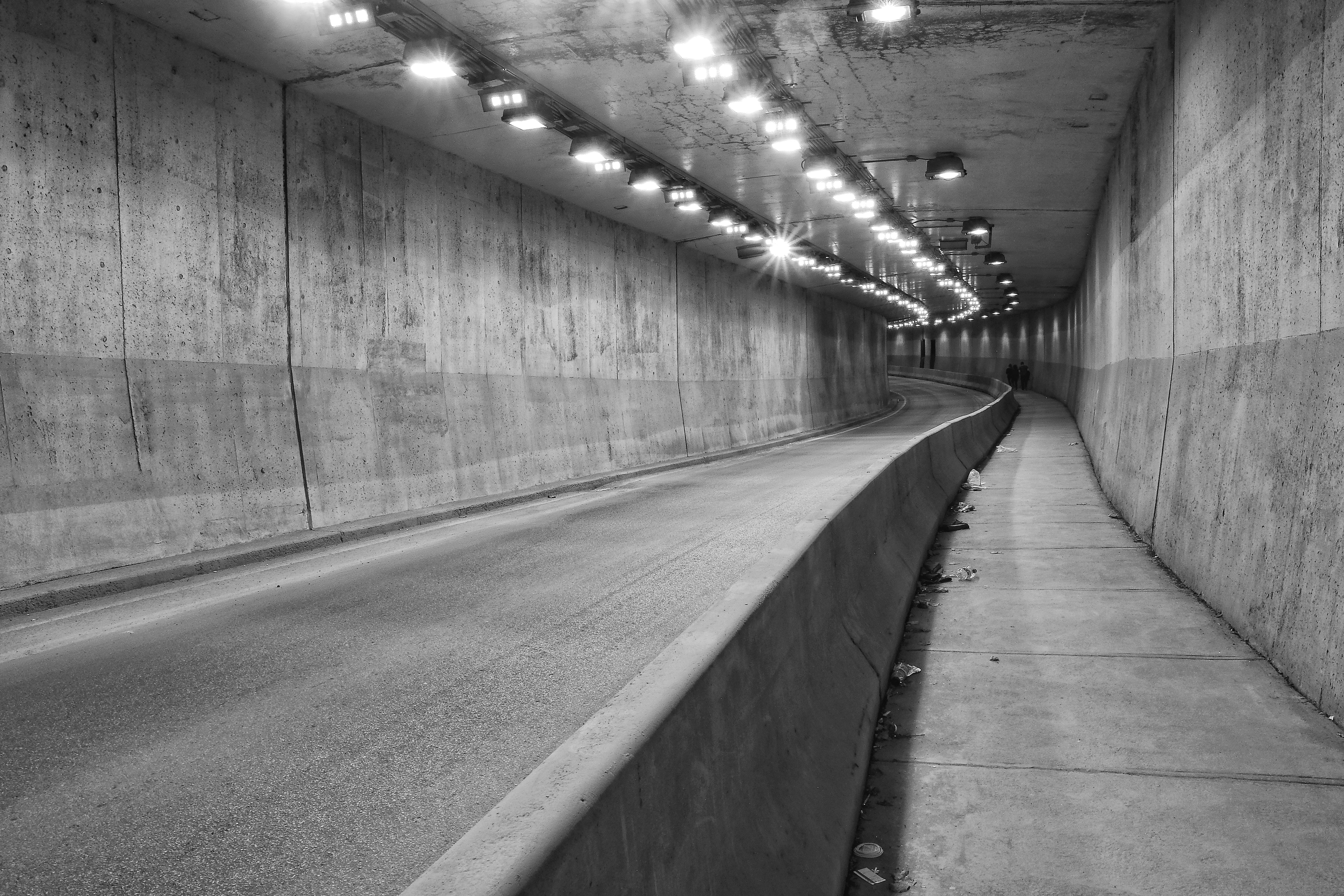 Black and white photo inside road tunnel with pedestrian sidewalk